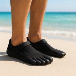 Voyageur sur une plage tropicale portant des chaussures 5 doigts Vibram FiveFingers noires, idéales pour la marche minimaliste et le voyage actif.