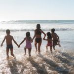 Séjour camping bord de mer avec enfants courant vers l'océan.